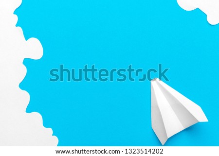Flying paper plane in the clouds on a blue background. Concept of flight, travel, transfer