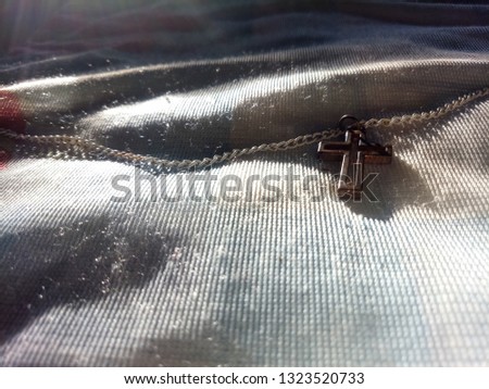 Close up view of golden Jesus christ cross necklace on cloth with shade light and shadow, God loving crucifix concept picture with selective focus