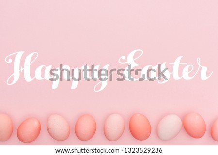 Happy Easter lettering with traditional painted eggs in row isolated on pink