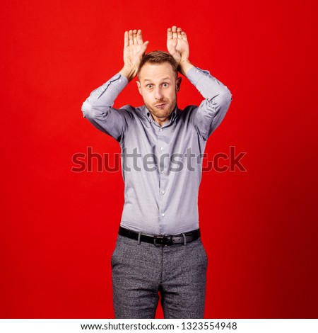 funny and crazy man with fingers on head as bunny ears over red background. people and emotion concept.