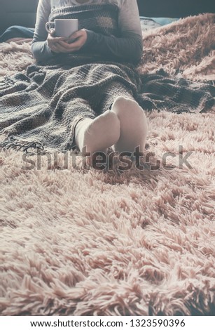 A girl with a cup of naya lies under a blanket. Recreation. Selective focus.