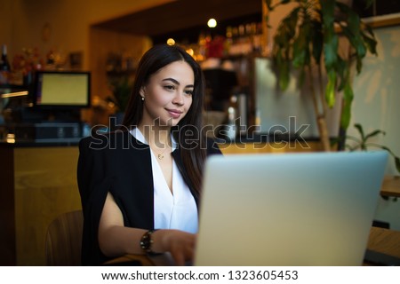 Beautiful woman smart university student having online learning via laptop computer during coffee break in restaurant. Female professional content writer typing article on netbook gadget. 