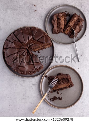 Top view composition with whole tasty chocolate cake, slices on gray plates on gray concrete background. Top view vertical picture. Concept of holiday dish