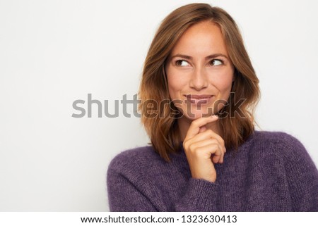 portrait of a young happy woman smiling and thinking on white background
