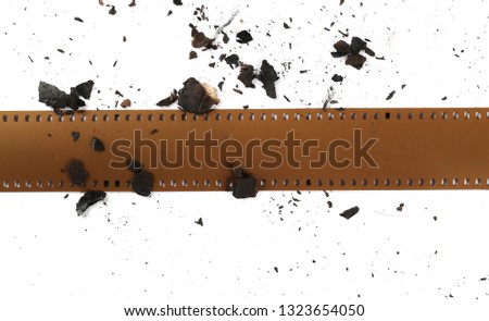 Burned and charred paper scraps and film strip isolated on white background, top view