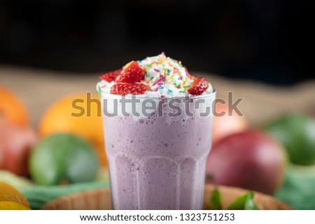 Glass of strawberry milkshake with whipped cream and fresh strawberries, on a wood background. tinting. selective focus.