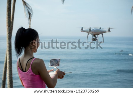 Woman controlling drone quadcopter on seaside