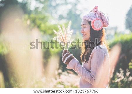 Spring, Young woman standing on an open field with flowers in the hand. She smiled warmly and enjoyed the morning sun.