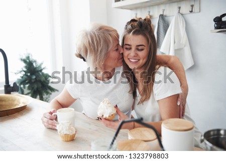 Cute kiss. Mother and daughter having good time in the kitchen.