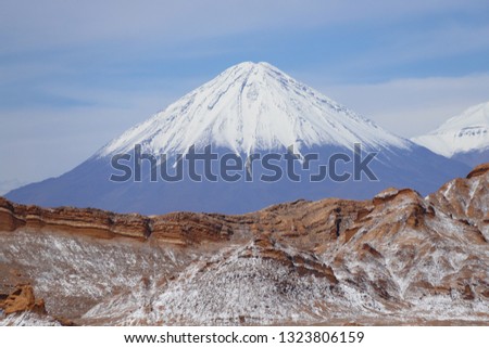 Valle de la Luna (Valley of the Moon) with the snowy Licancabur volcano in the background, the white in the foreground is salt, Atacama Desert, Chile