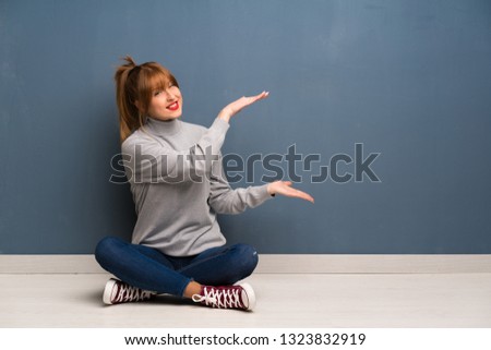 Redhead woman siting on the floor holding copyspace to insert an ad