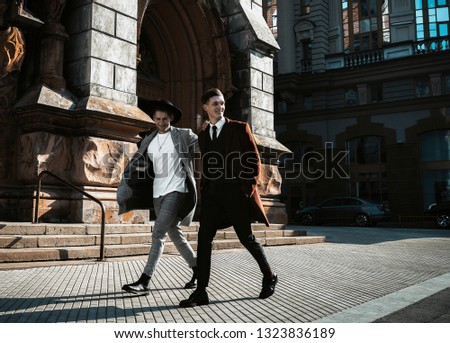 Two fashion beautiful man models posing on city street. Wearing in classic and casual closes. Suit, coat, shirt, sweater, boots. Man model street test. Royalty-Free Stock Photo #1323836189