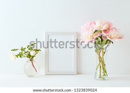 Mockup with a white frame and pink peonies in a vase on a white background