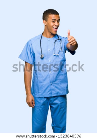 Surgeon doctor man giving a thumbs up gesture because something good has happened on isolated background