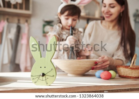 Close up view of the rabbit face. Mother and daughter in bunny ears at easter time have some fun in the kitchen at daytime.