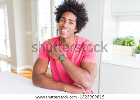 African American business man wearing pink casual t-shirt cheerful with a smile of face pointing with hand and finger up to the side with happy and natural expression on face