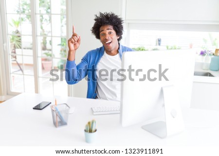 African American man working using computer pointing finger up with successful idea. Exited and happy. Number one.