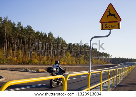 A road sign warns motorcyclist that there is a deers or other wildlife animals crossing the road ahead