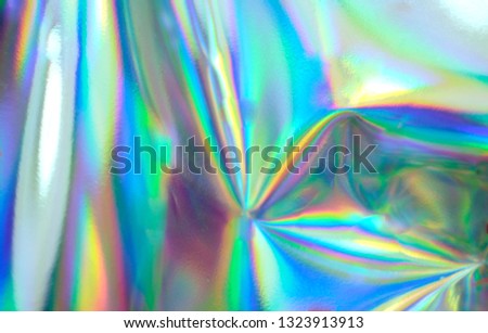 Holographic real texture, wrinkled foil in blue pink green colors with scratches and irregularities. Royalty-Free Stock Photo #1323913913