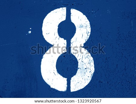Number 8 in stencil on metal wall in navy blue tone. Abstract background and texture for design.