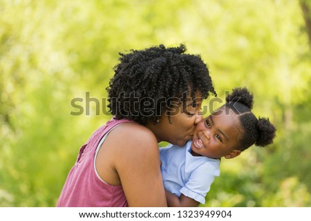 African American mother kissing her daughter.