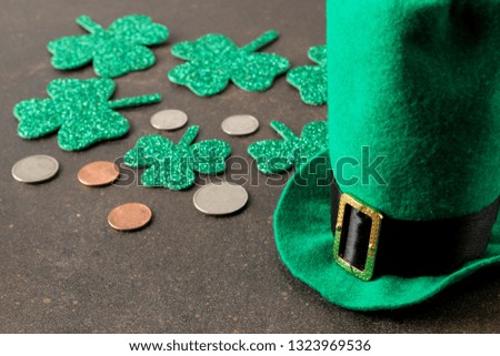 St.Patrick 's Day. celebration. Green leprechaun hat, money and clover leaf on a brown background.