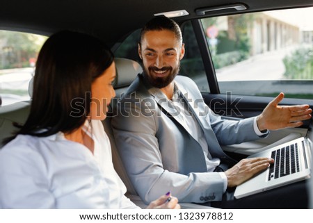 Young businesswoman and  businessman having discussing at the back of a taxi