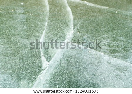 cracked thin ice on the pond, frozen water bubbles