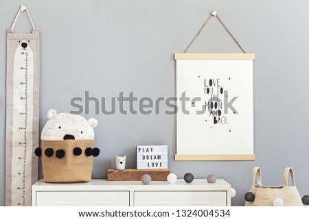 Stylish and cute scandinavian decor of  child room with mock up poster, white shelf, natural toys, hanging kid measure  basket for accessories and teddy bears. Minimalistic concept of interior.