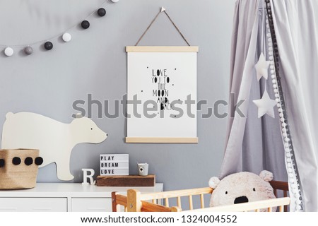 Stylish and cute scandinavian decor of  newborn baby room  with mock up poster , white design furnitures, natural toys, hanging grey canopy with wooden cradle, pillows, accessories and teddy bears. 