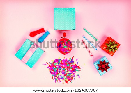 Concept: birthday party. Gift boxes, red and gold bow, colorful candy, balloons on a pink pastel minimalist background. Flat lay