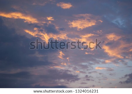 Evening clouds on a darkening sky, background, the light of the setting sun.