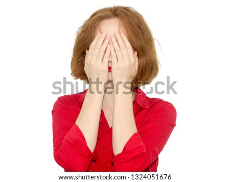 The woman in red clothes covered her face with hands. She feels great fear. Girl isolated on white background.