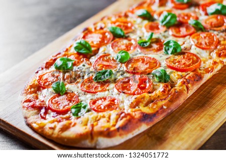 oval Pizza with Mozzarella cheese, Tomatoes, pepper, Spices and Fresh Basil. Italian pizza. Pizza Margherita or Margarita on wooden table background