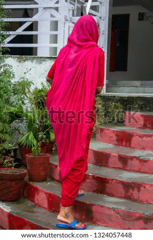 Woman climbing stairs on her back, dressed in a sari, in India
