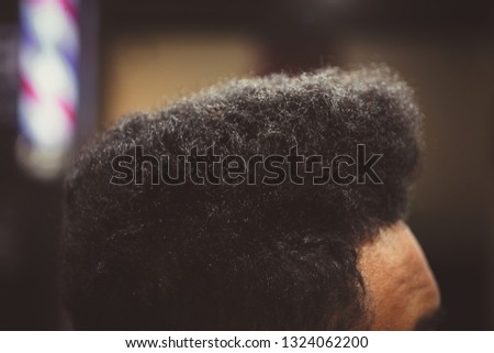 Black young man cuts his hair in barbershop.Close up shot of African male model cutting curly locsk in barber shop salon. Male beauty treatment  process in close up