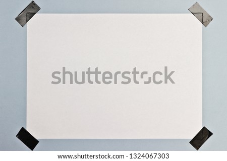 white sheet of paper glued to the blue wall with black electrical tape