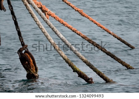 Graphic view on five mooring ropes going down from the boat to the water. One of them on a pulley.