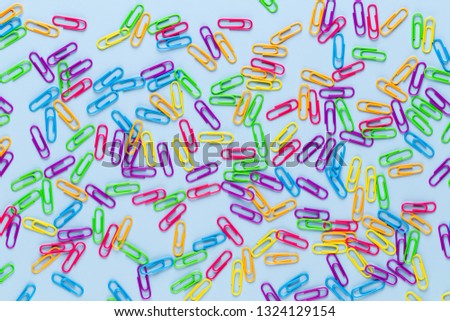 Color paper clips on blue background, copy space. Top view, flat lay. Back to school, college, education concept. Collection of colorful paperclips. Abstract background.