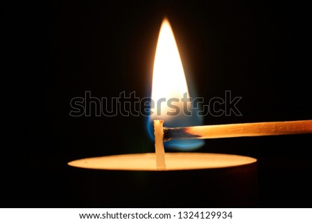 A match at the moment it lights a small candle