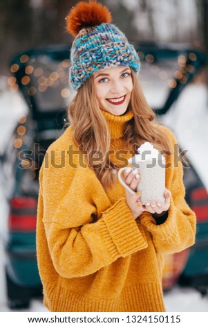 Beautiful girl in the winter in the forest with a cup of cream