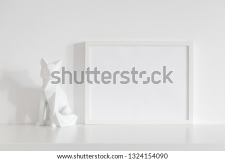 Frame mock up and origami fox design home decor near white wall.