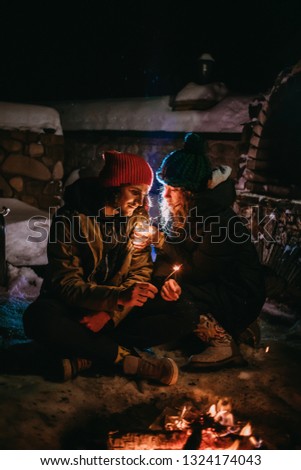 Loving couple in colored hats sitting near the fire.
