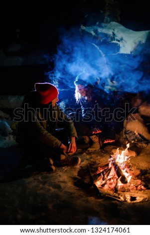 The guy and the girl are sitting near the fire. Romantic night.