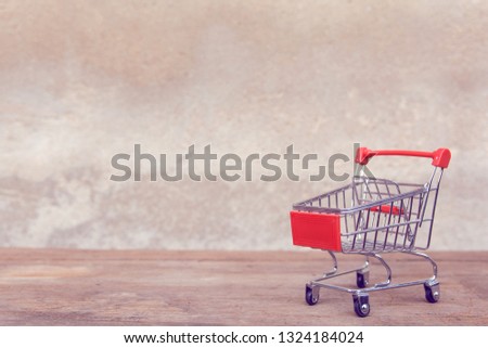 Shopping concept : Empty red shopping cart on brown wood table. online shopping consumers can shop from home and delivery service. with copy space