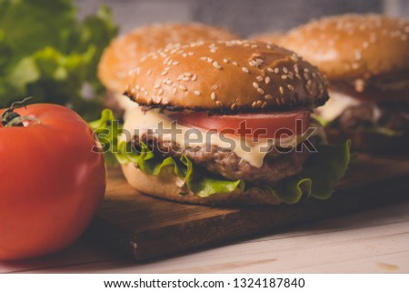 Нamburger or sandwich on brown paper. Delicious sandwich hamburger with meat, cheese and fresh vegetable. Hamburger or sandwich is the popular fast food for brunch or lunch. Juicy cheeseburger
