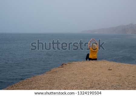 Pretty blond girl watching the sea. Portrait of a happy woman relaxing sitting and watching the sea in the background. 