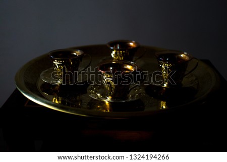Traditional golden egyptian brass coffee set isolated on the black background. Middle eastern coffee maker with glasses. Golden cups on the black background.