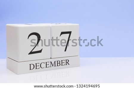 December 27st. Day 27 of month, daily calendar on white table with reflection, with light blue background. Winter time, empty space for text