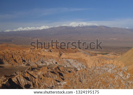 View of the landscape of rocks of the Mars Valley (Valle de Marte) and snow-covered volcanoes, Atacama Desert, Chile